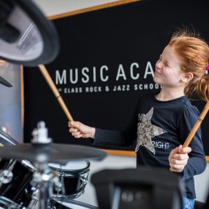 Junges Mädchen spielt Schlagzeug an der Music Academy