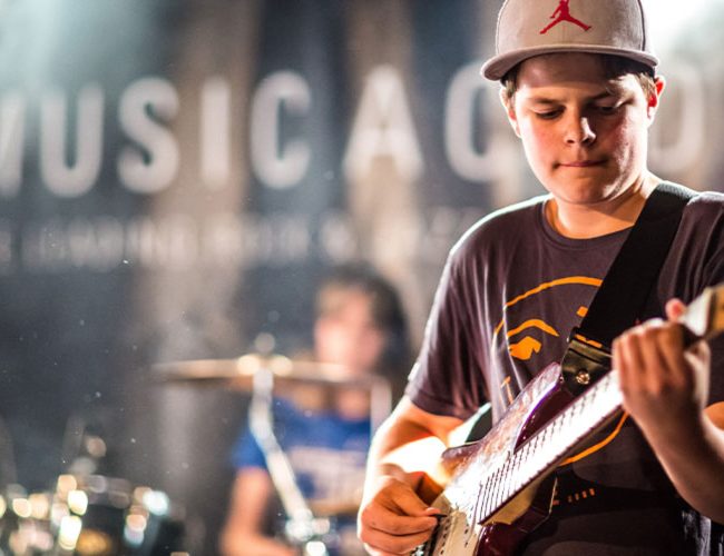 Schüler spielt in seiner Band der Music Academy Gitarre